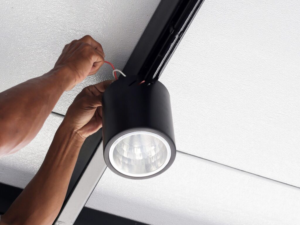 Jemand ist eine schwarze Lampe an der Decke am montieren.