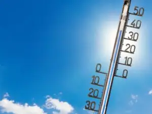 Blauer HImmel mit Sonnenschein, ein paar Wolken sind im Bild und ein Thermometer