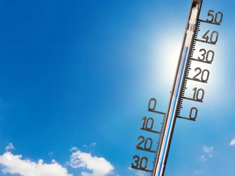 Blauer HImmel mit Sonnenschein, ein paar Wolken sind im Bild und ein Thermometer